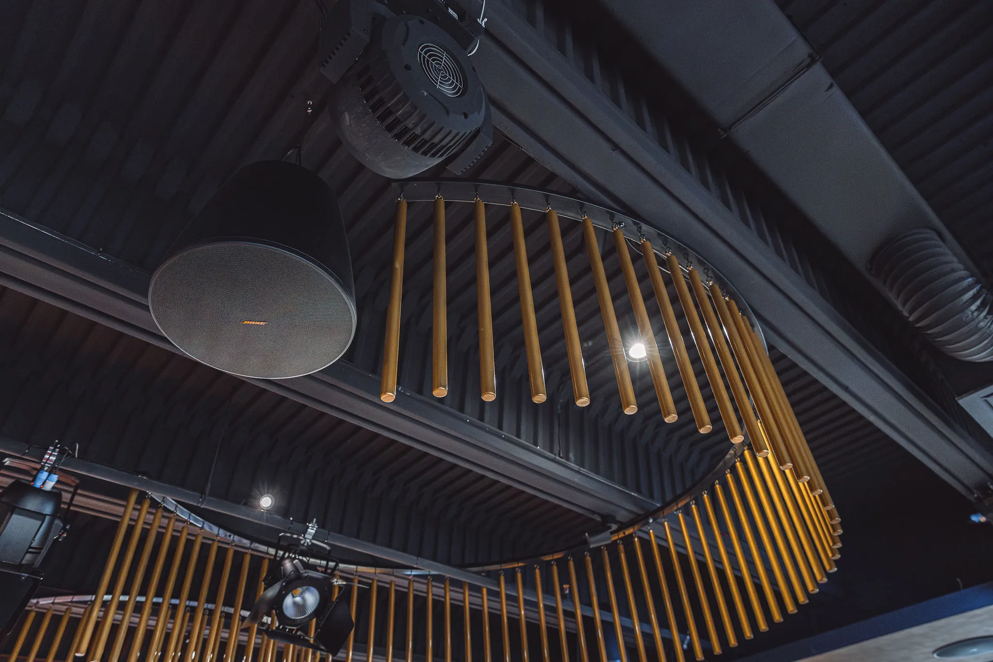Bose pendant speaker integrated among gold chandelier elements in a premium venue — Cosmic Production invisible audio design