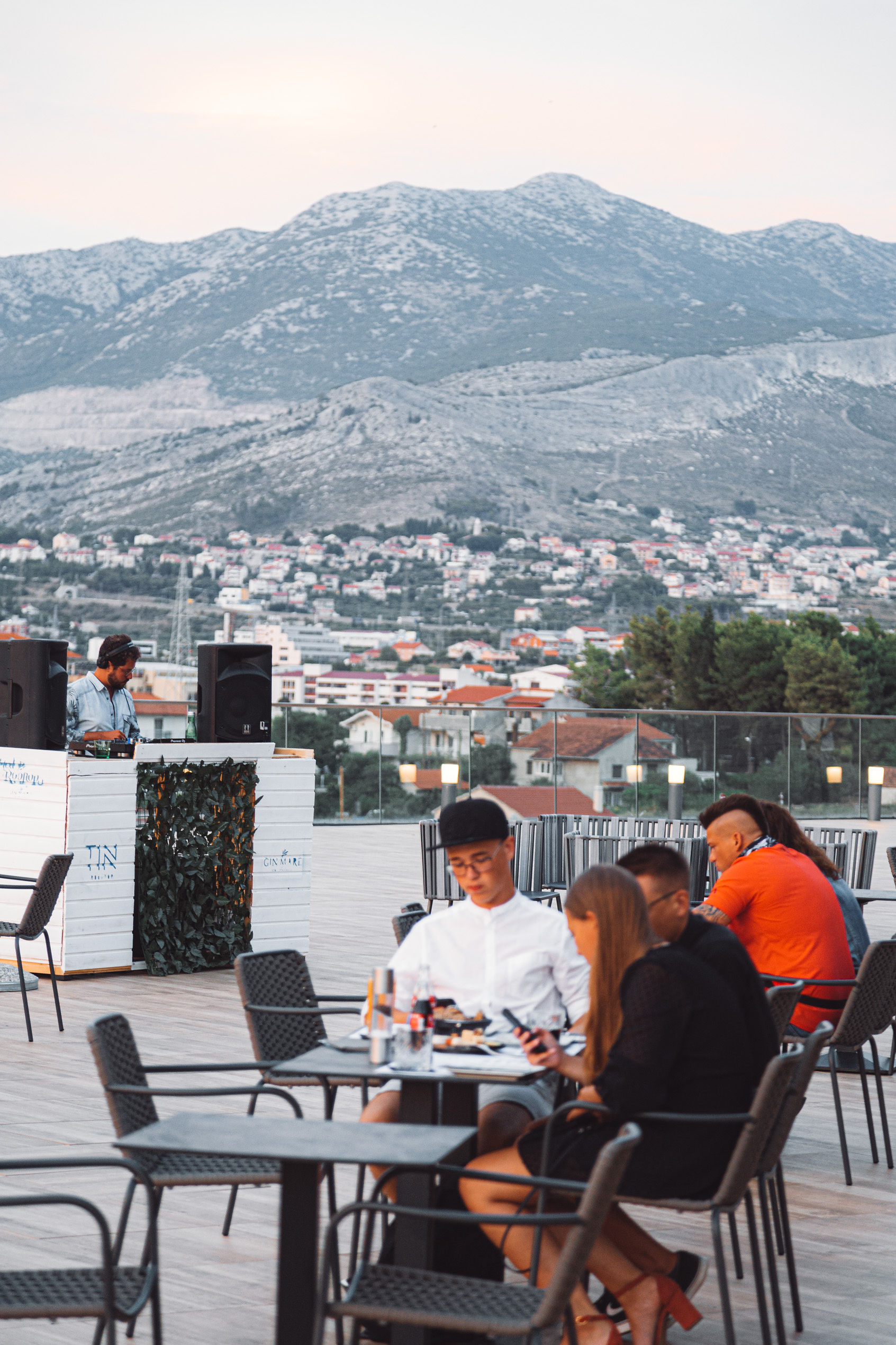 DJ Leo performing a rooftop set at Tin Restaurant in Split with diners and mountain views — Cosmic Production residency