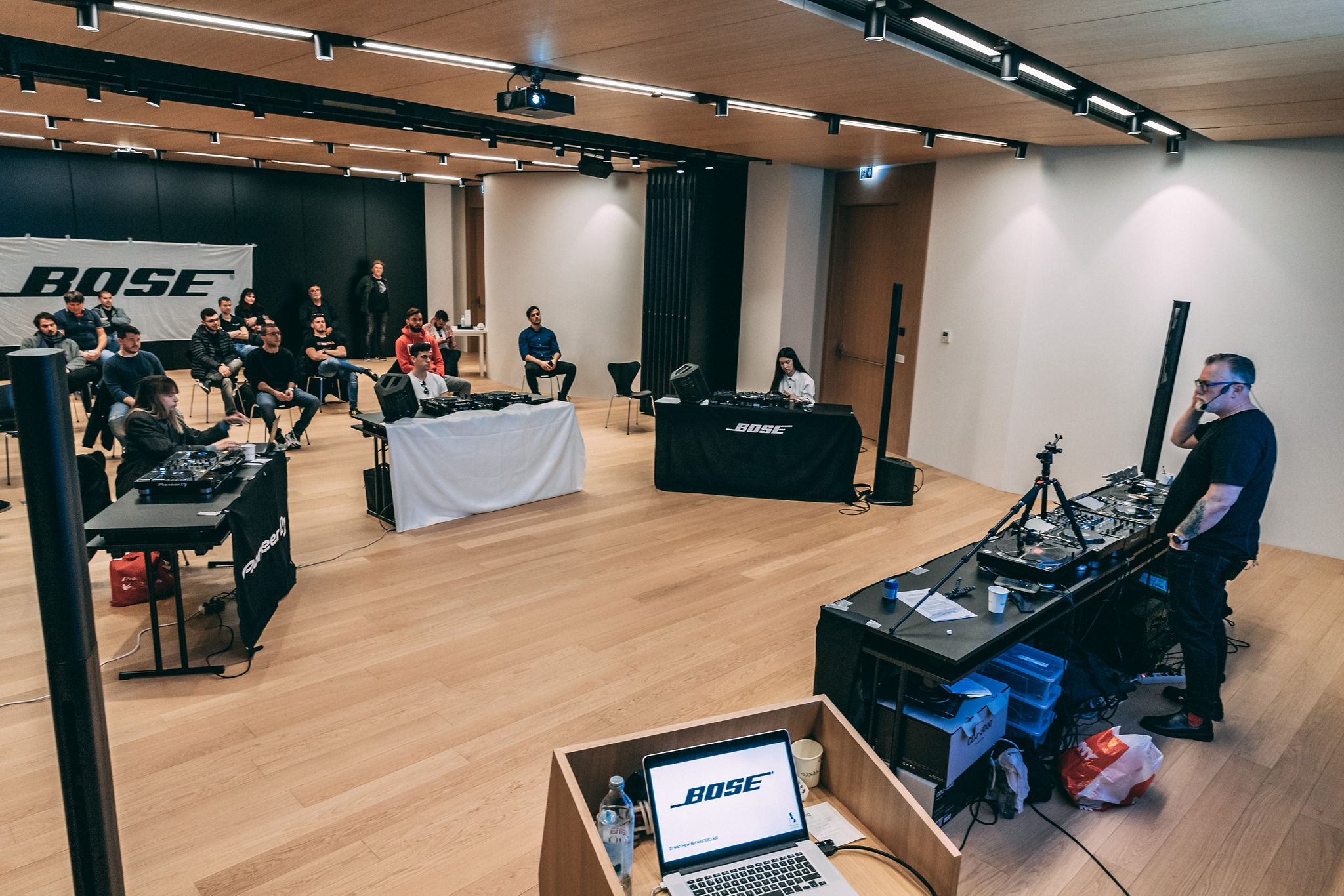 Full DJ masterclass training room with Bose Professional branding, multiple Pioneer DJ stations, and students practising — Cosmic Production