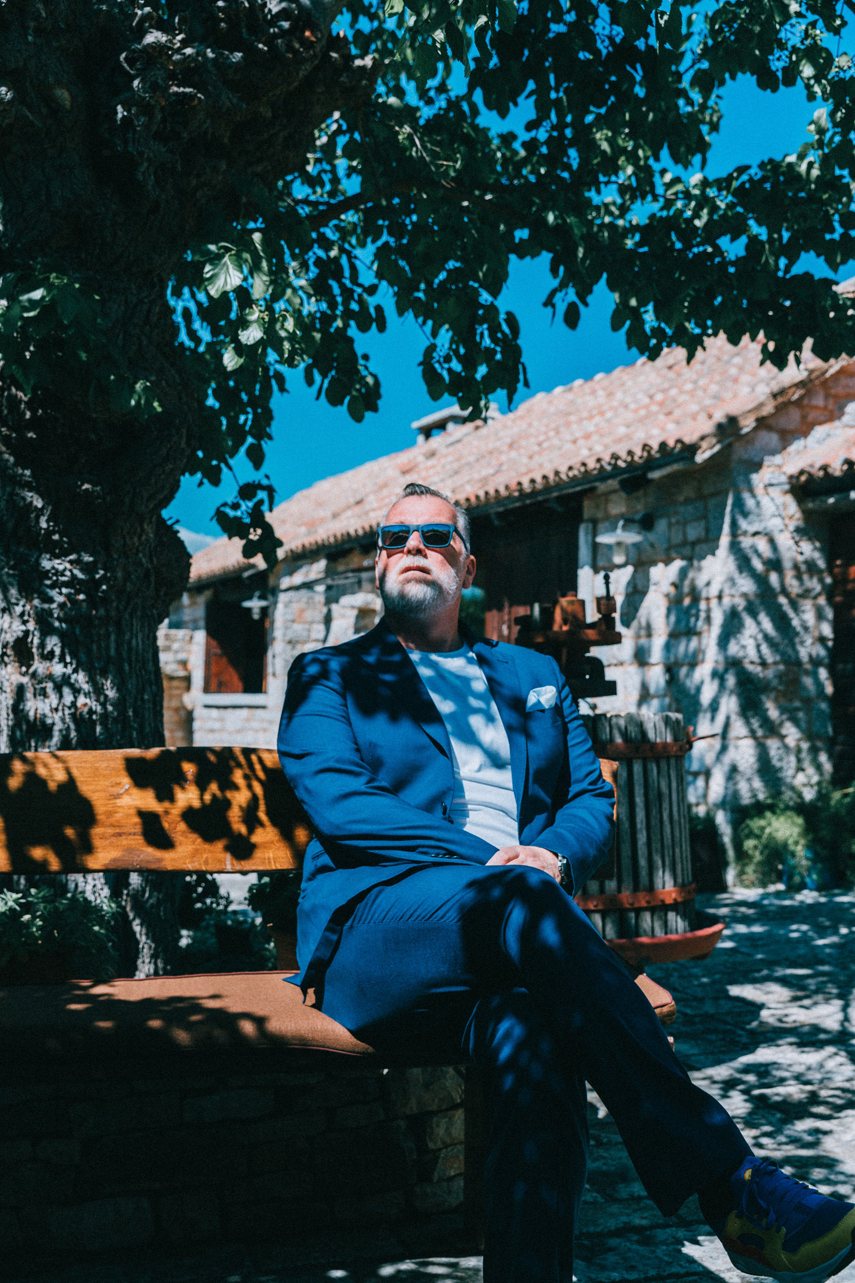 DJ Matthew Bee in blue suit outside a traditional Croatian stone village