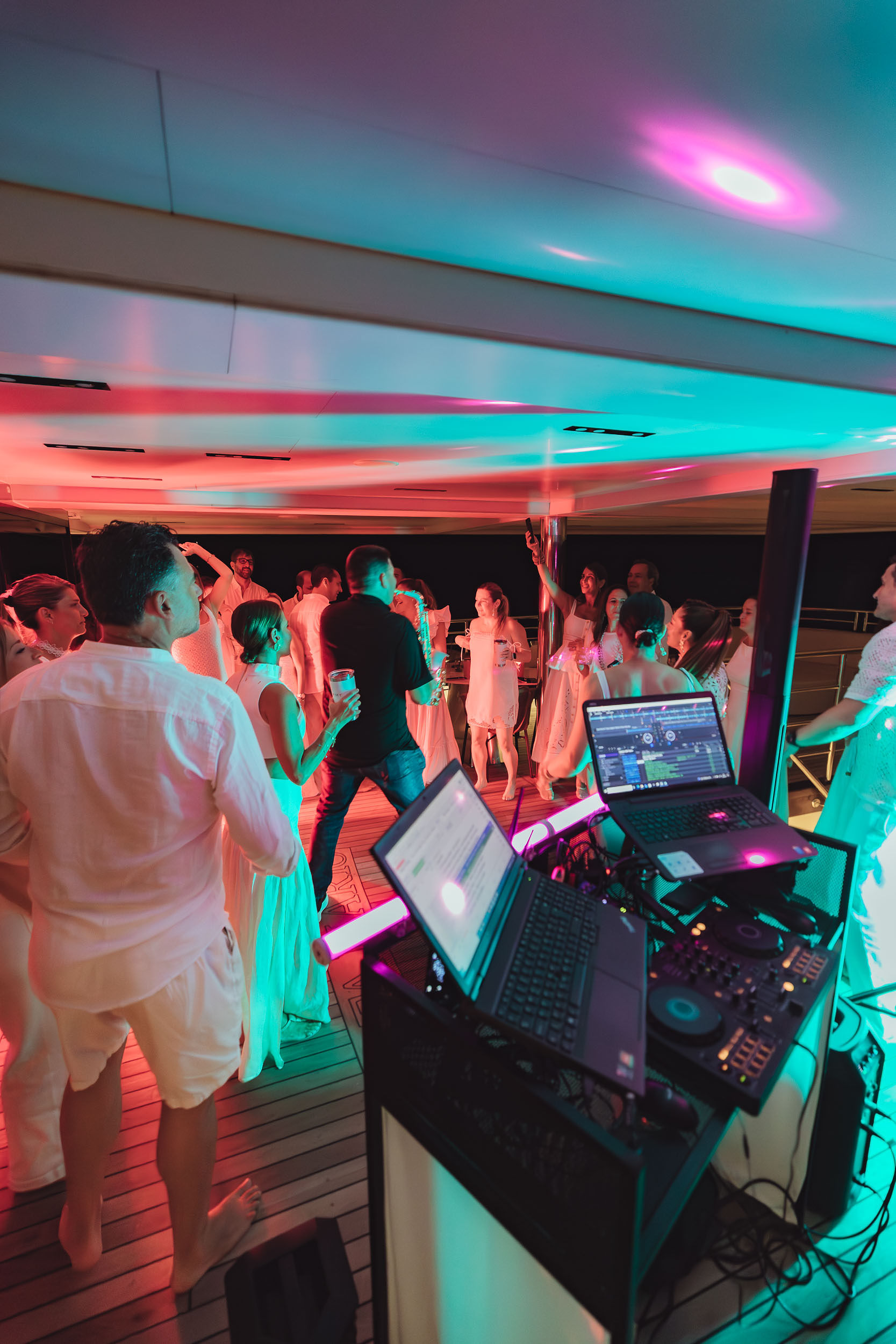 Pioneer CDJ setup na plesnom podiju jahte s rozom i tirkiznom rasvjetom — Cosmic Production yacht party produkcija