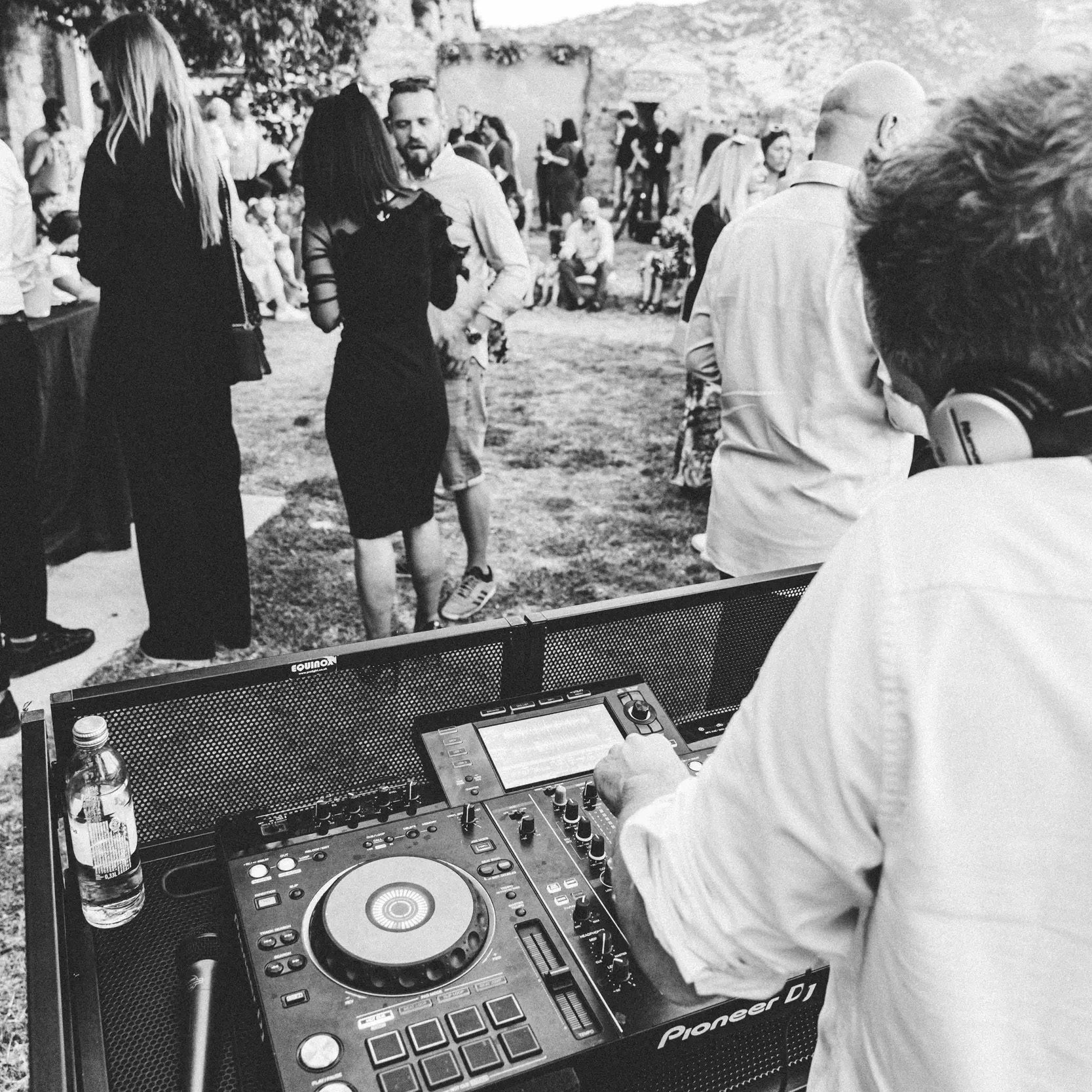DJs For Events in Croatia - Cosmic Production DJ Agency and AV Company DJs For Events in Croatia - Cosmic Production DJ Agency and AV Company. The image features a crop of a wide angle shot, taken from behind the DJ who is playing on his DJ mixer at a premium dinner experience event outdoors at Klis Fortress near Split, Croatia.